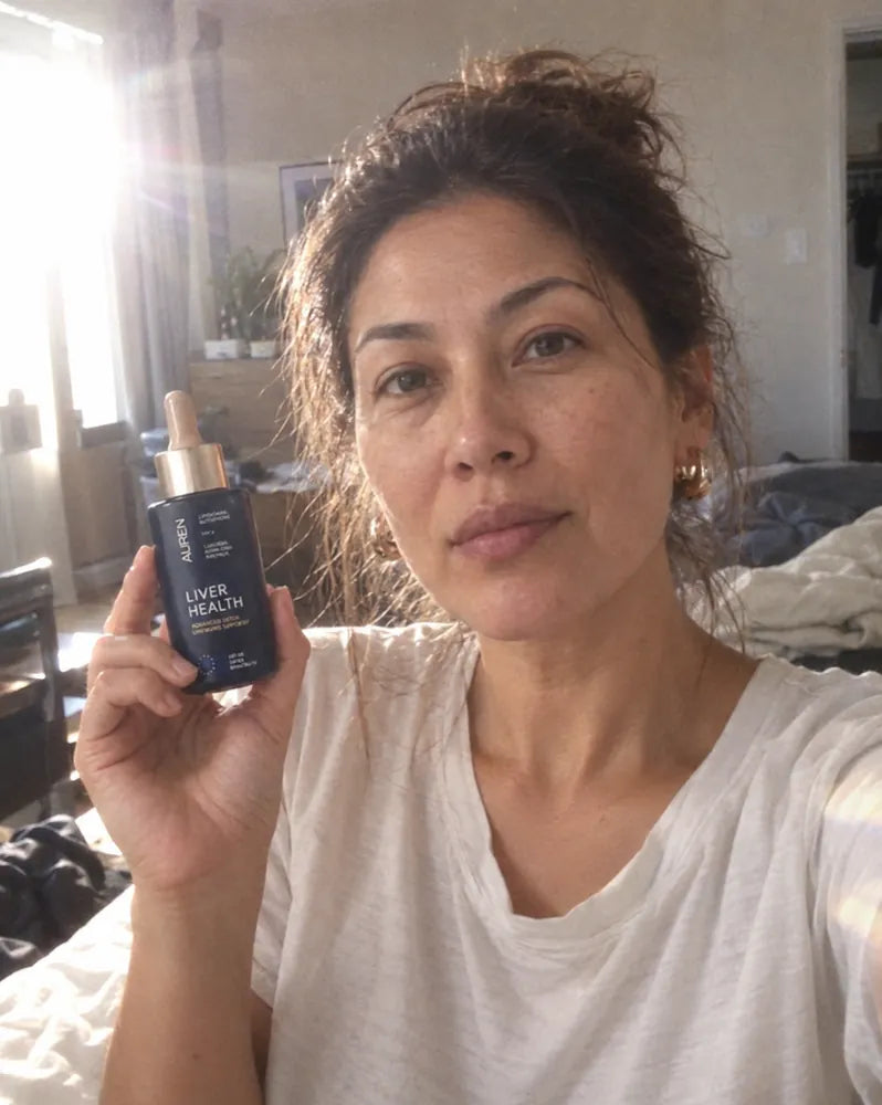 Woman holding the AUREN bottle in a sunlit bedroom